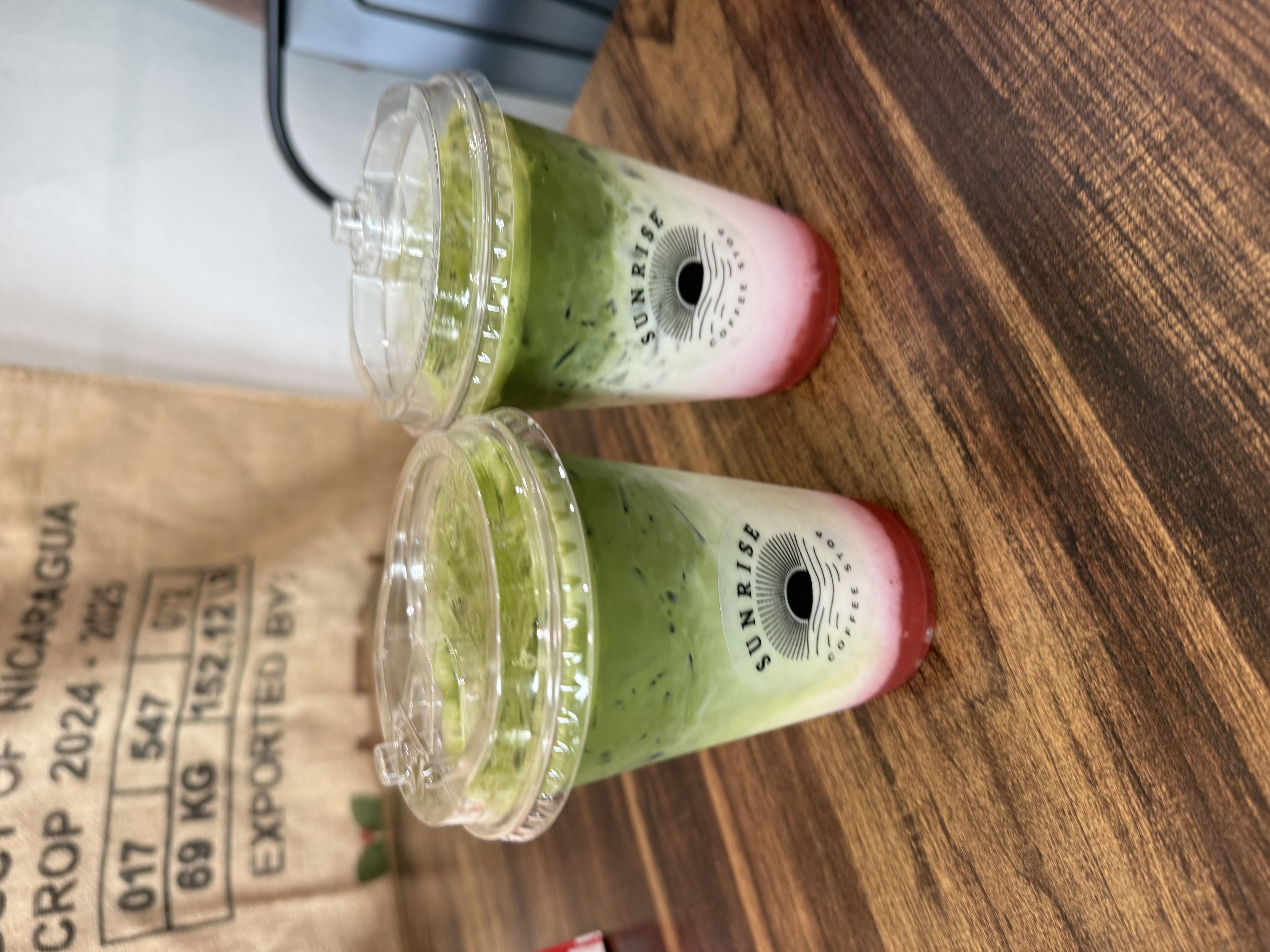Two iced strawberry matcha lattes in Sunrise Coffee Stop cups
